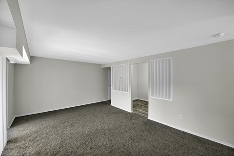 an empty living room with gray carpet and white walls